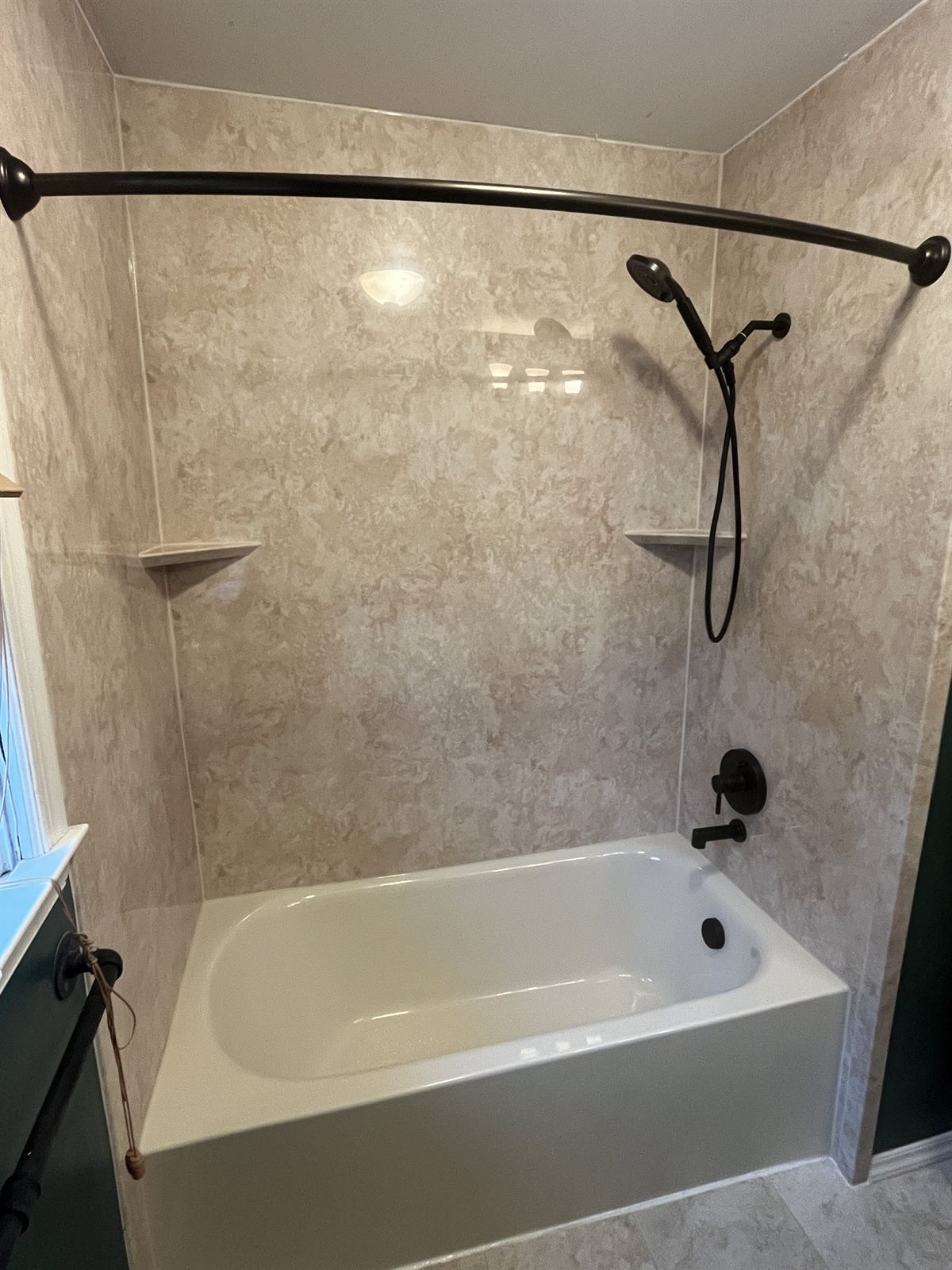 New white tub with travertine look acrylic walls and oil rubbed bronze fixtures